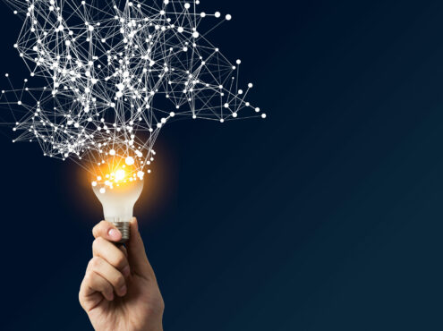 Une main tient une ampoule qui brille. Des réseaux connectés sortent de cette ampoule.