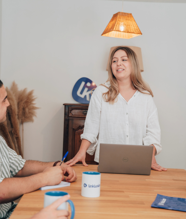Une femme souriante et enthousiaste, animant une formation engageante, regardant attentivement les participants avec bienveillance.