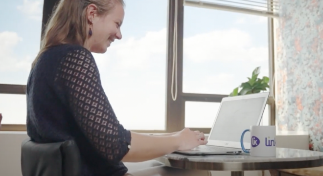 Femme souriante devant son ordinateur avec un mug Linklusion