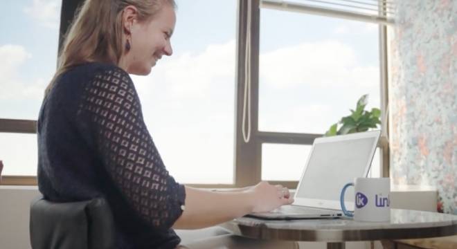 Femme souriante devant son ordinateur avec un mug Linklusion