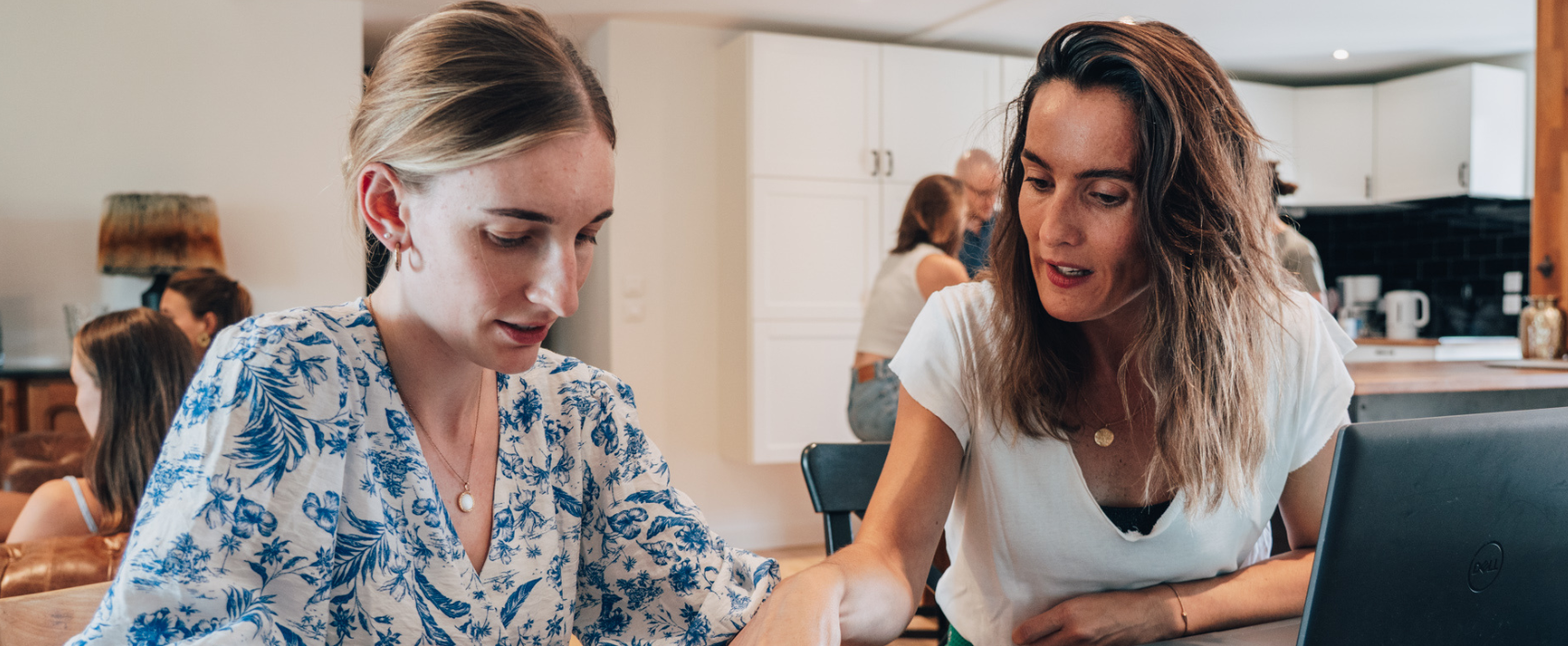 Photo de 2 personnes assises autour d'une table avec un ordinateur.