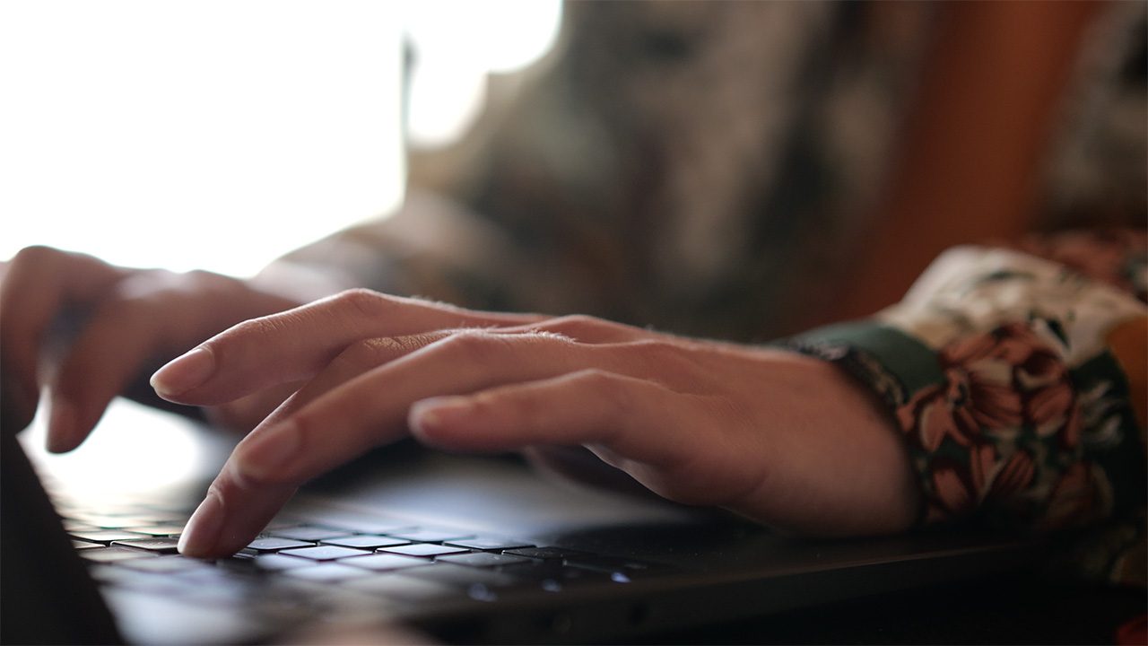 Des mains tapent sur le clavier d'un ordinateur.