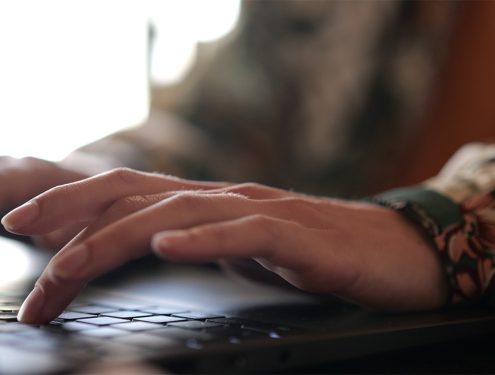 Des mains tapent sur le clavier d'un ordinateur.